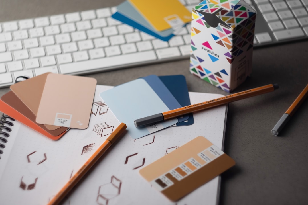 Swatchos color swatch cards with CMYK and RGB hex values showing being used by a graphic designer on a graphic designer's desk
