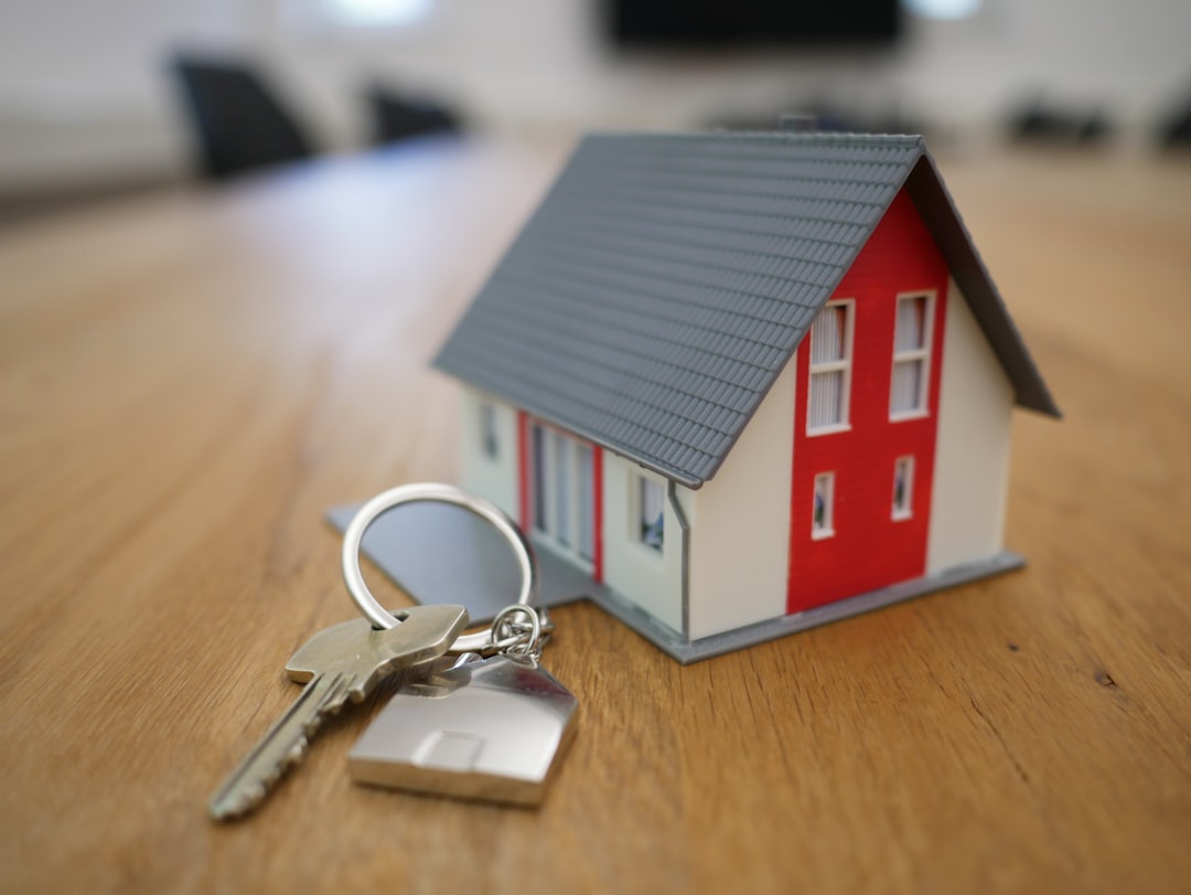 Maqueta de una casa en miniatura y un juego de llaves sobre una mesa de madera — la imagen cliché de la compra de vivienda, usada aquí como tal.